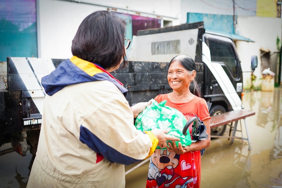 SM Supermalls Regional Operations Head for Bulacan and CAMANAVA, Ana Datu, an SM employee-volunteer, delivers immediate relief to a resident impacted by flooding.